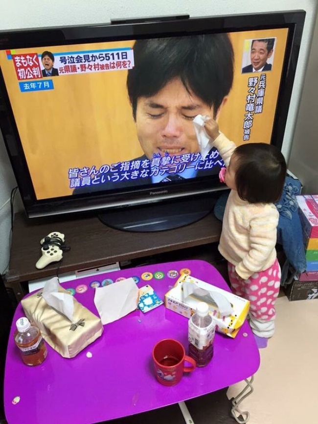 Un bébé qui tente d’essuyer les larmes d'un homme qui pleure à la télé