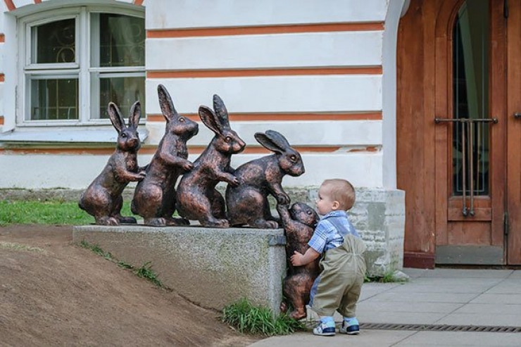 Un enfant aide un lapin à grimper une sculpture