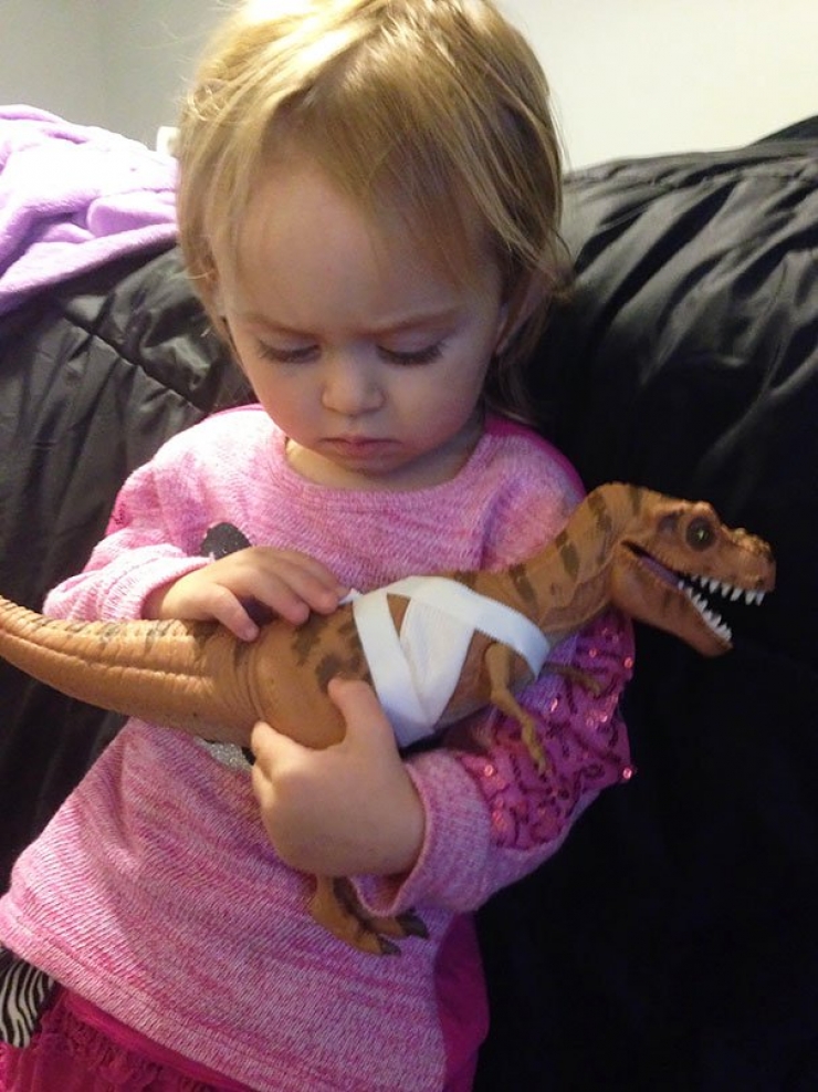 Une fille de 2 ans qui réconforte son dinosaure blessé