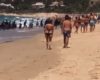 Des migrants en bateau débarquent sur une plage remplie de touristes