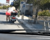 Une fille blonde tente de démarrer son scooter en appuyant sur la béquille