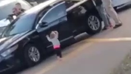 Une petite fille sort d'une voiture les mains en l'air face à des policiers