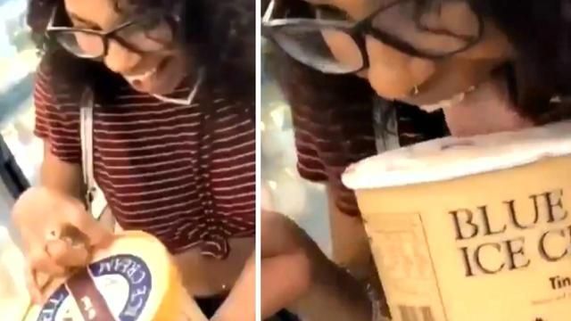 Une fille lèche une crème glacée puis la remet dans le congélateur d’un supermarché