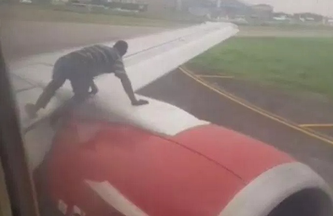 Un homme en train de monter sur l’aile d’un avion qui s'apprêtait à décoller