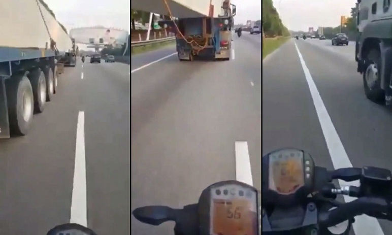 Un motocycliste en train de passer sous un camion