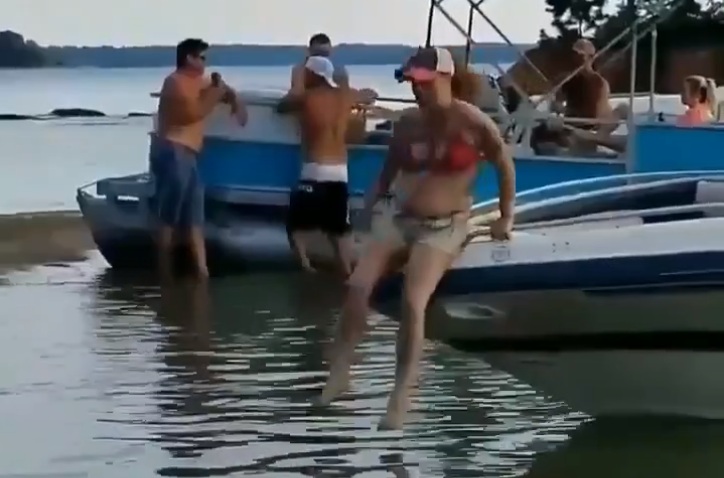 Cette femme tente d'aller à l’eau en passant par la partie avant de son bateau